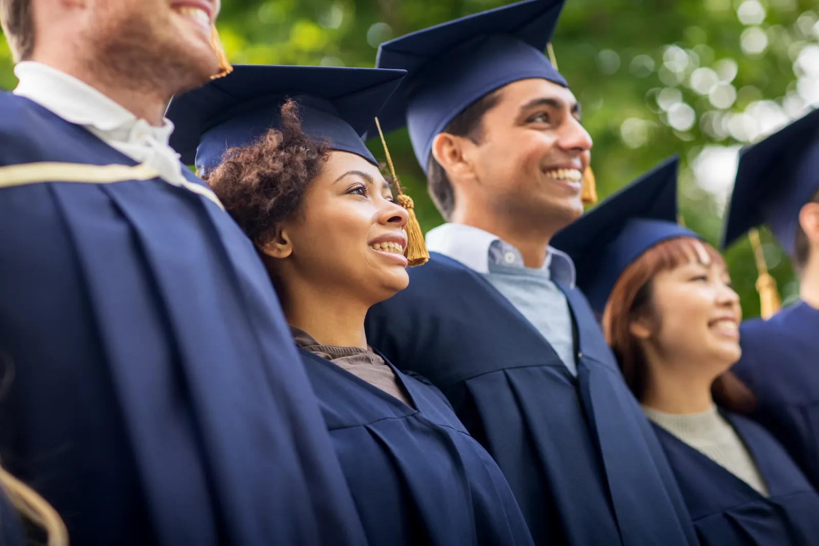 Smiling graduates in navy caps and gowns