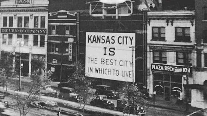 A vintage photo of a Kansas City street with a sign reading "Kansas City is the best city in which to live"