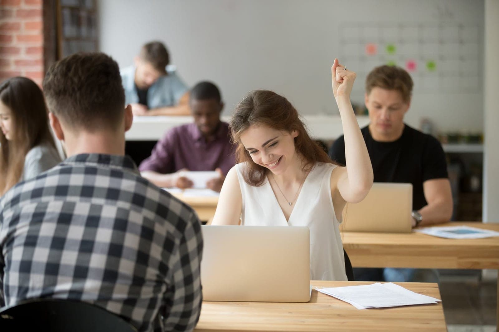 A woman celebrating at her laptop in a shared office