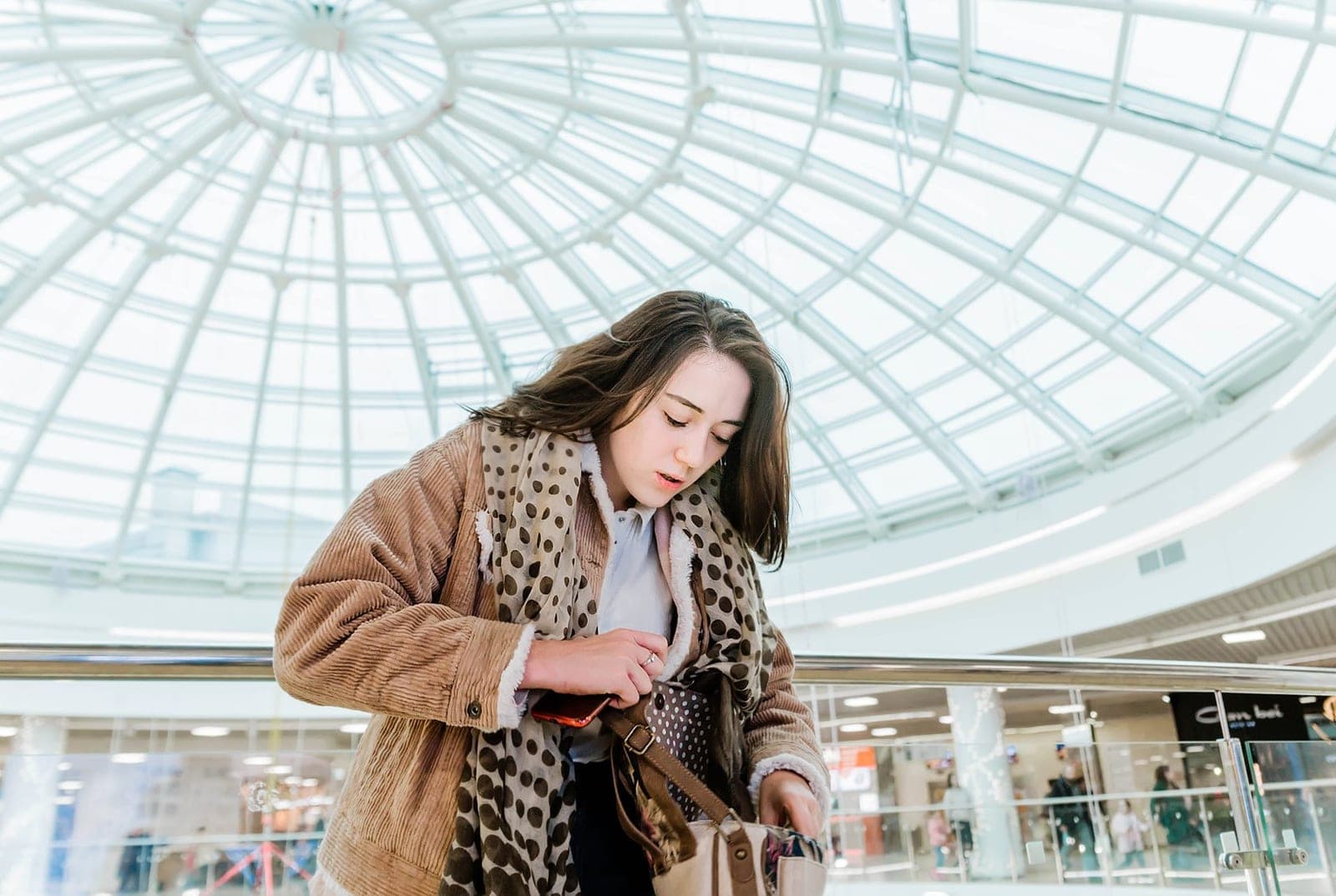 A woman searching through her coat pockets in a shopping mall